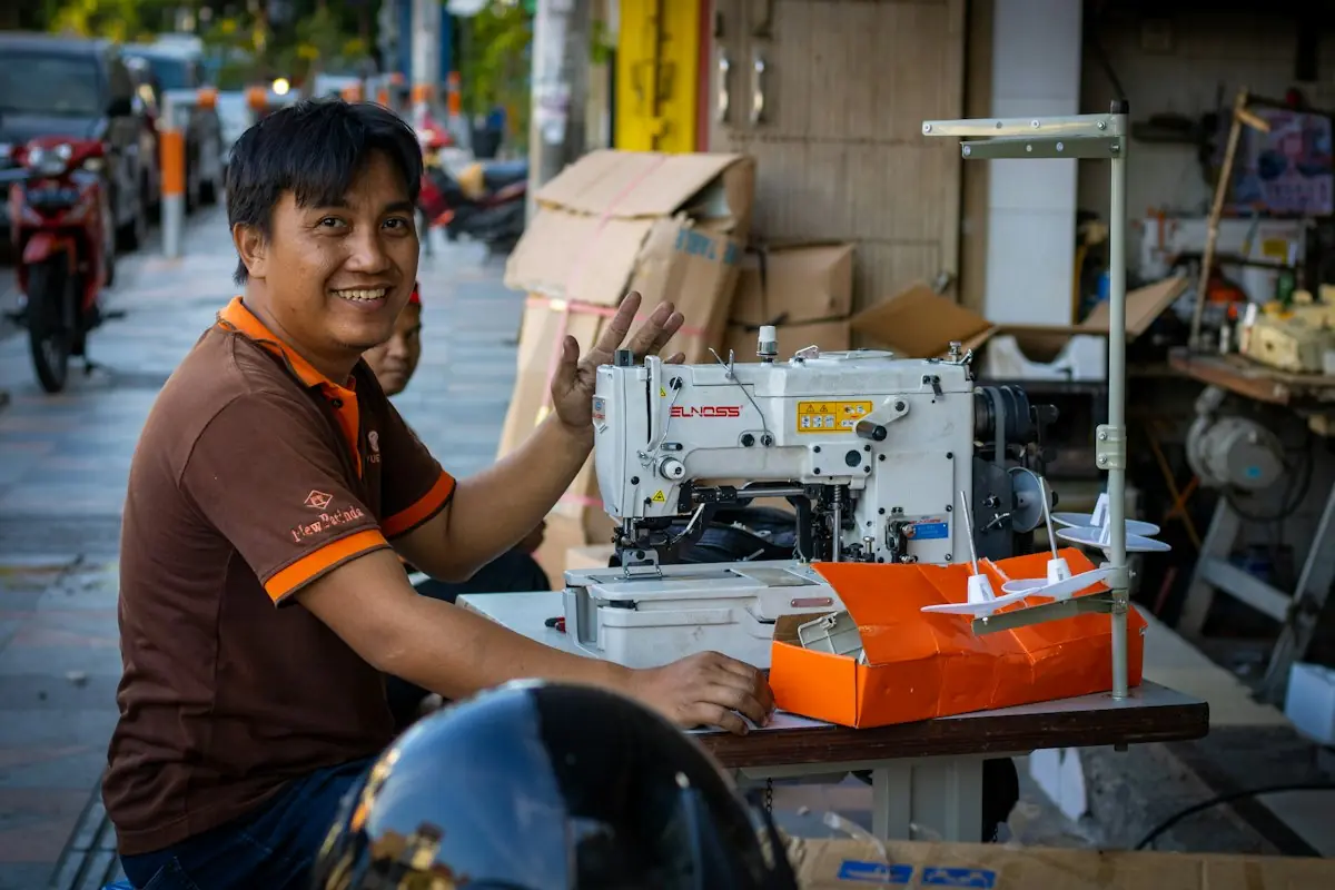 Pemilik usaha konveksi tersenyum di bengkel kerjanya